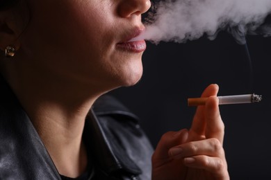 Photo of Woman smoking cigarette on black background, closeup
