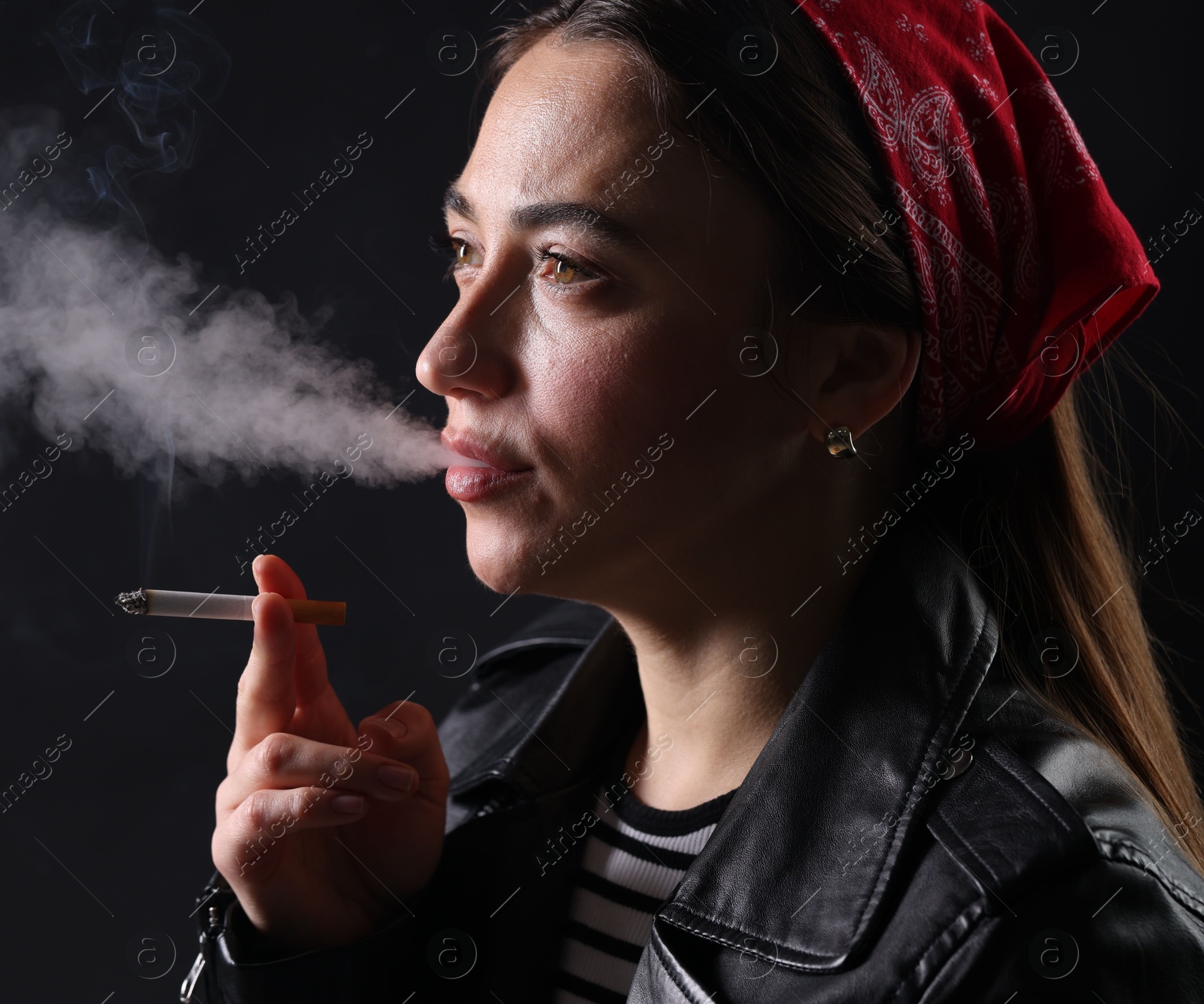 Woman in bandana smoking cigarette on black background, closeup Photo of Woman in bandana smoking cigarette on black background, closeup