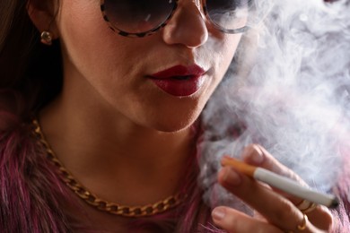 Photo of Woman in sunglasses smoking cigarette, closeup. Bad habit
