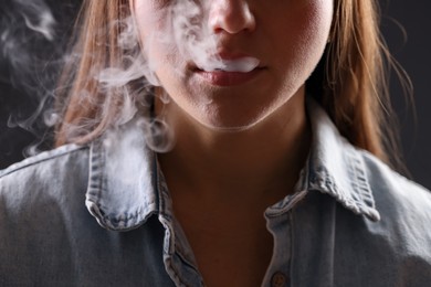 Photo of Woman in shirt smoking cigarette on dark background, closeup. Bad habit