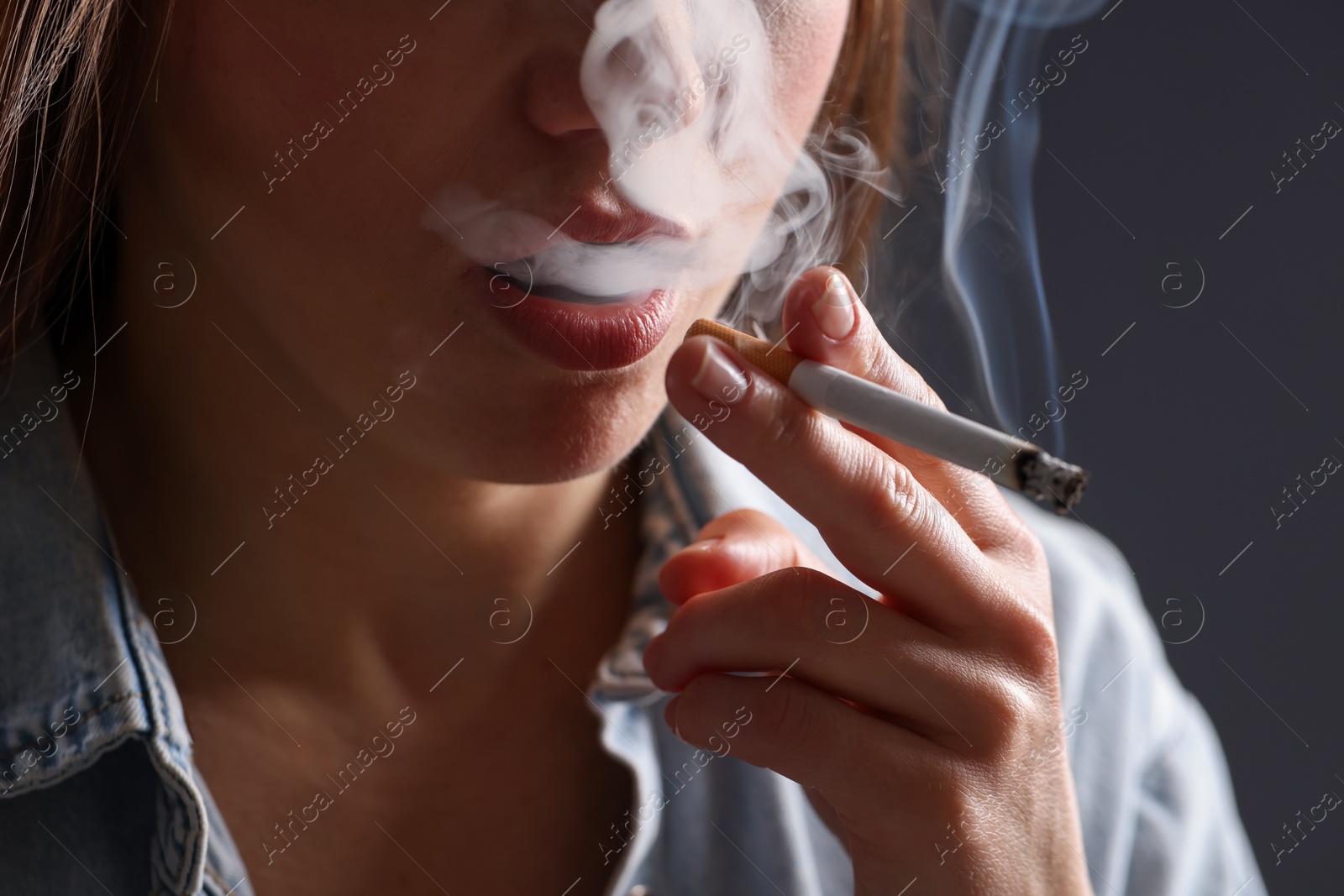 Woman in shirt smoking cigarette on dark background, closeup. Bad habit Photo of Woman in shirt smoking cigarette on dark background, closeup. Bad habit