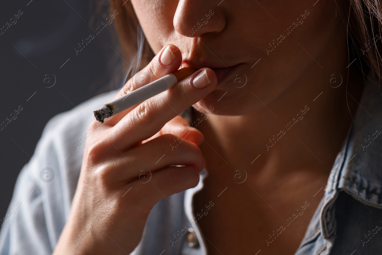 Woman in shirt smoking cigarette on dark background, closeup. Bad habit Photo of Woman in shirt smoking cigarette on dark background, closeup. Bad habit