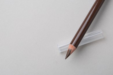 Photo of Brown eyebrow pencil on light background, top view. Space for text