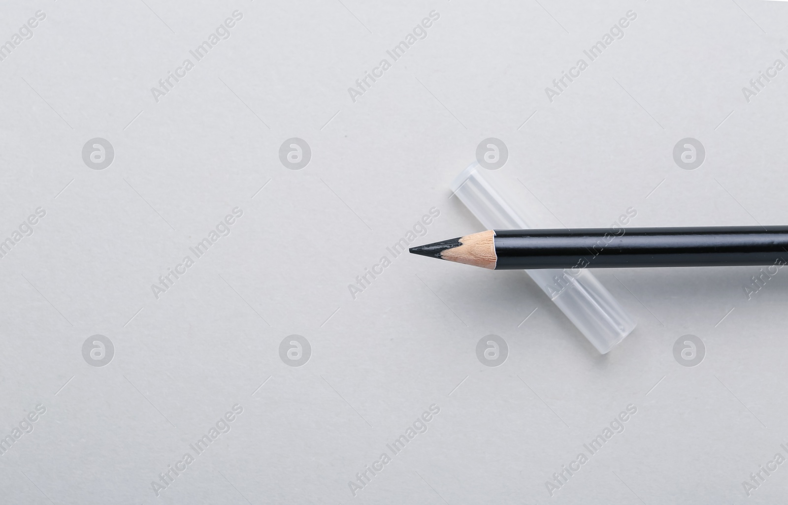 Black eyebrow pencil on light background, top view. Space for text Photo of Black eyebrow pencil on light background, top view. Space for text