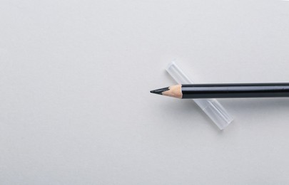 Photo of Black eyebrow pencil on light background, top view. Space for text