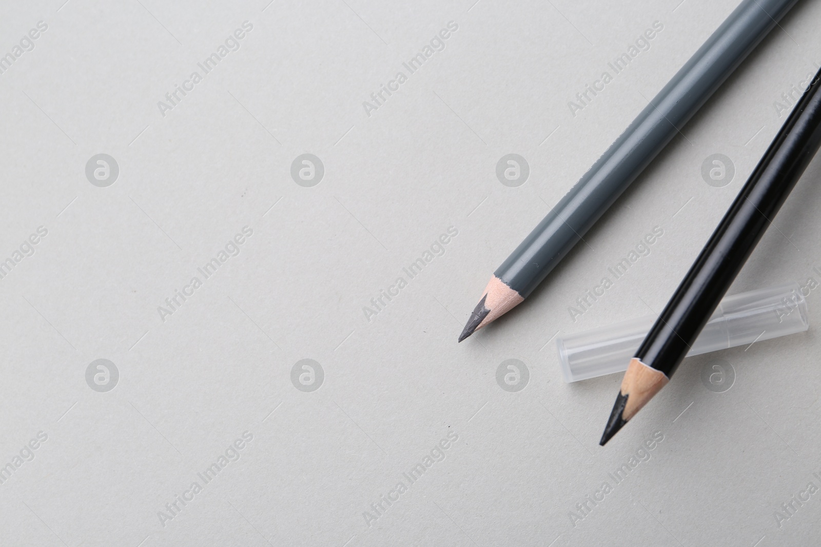Two different eyebrow pencils on light background, top view. Space for text Photo of Two different eyebrow pencils on light background, top view. Space for text