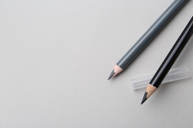 Photo of Two different eyebrow pencils on light background, top view. Space for text