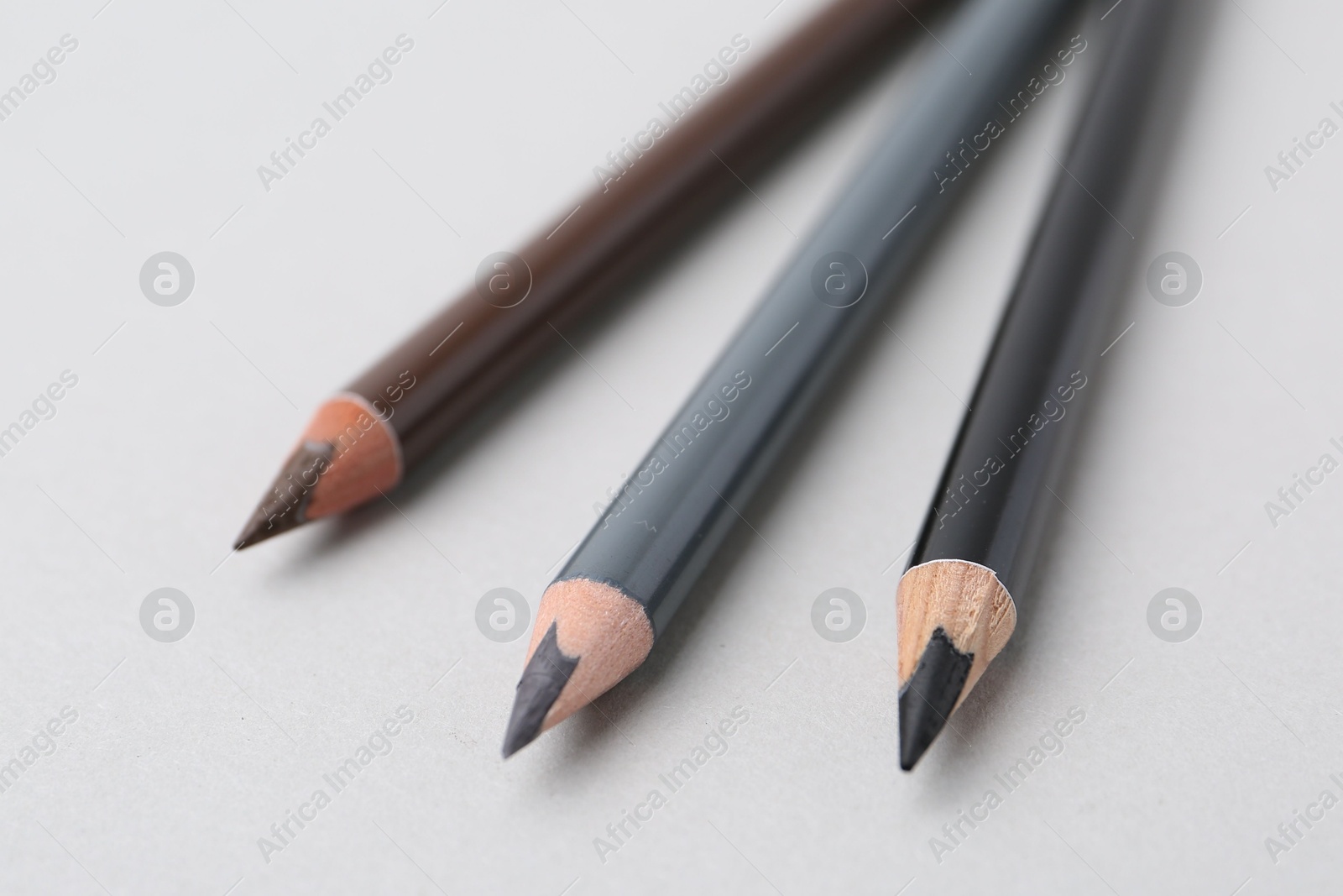 Three different eyebrow pencils on light background, closeup Photo of Three different eyebrow pencils on light background, closeup