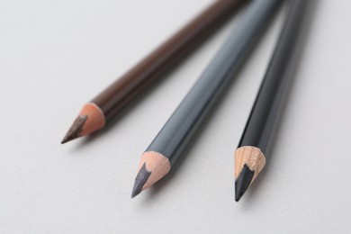 Photo of Three different eyebrow pencils on light background, closeup