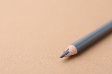 Photo of Grey eyebrow pencil on beige background, closeup. Space for text
