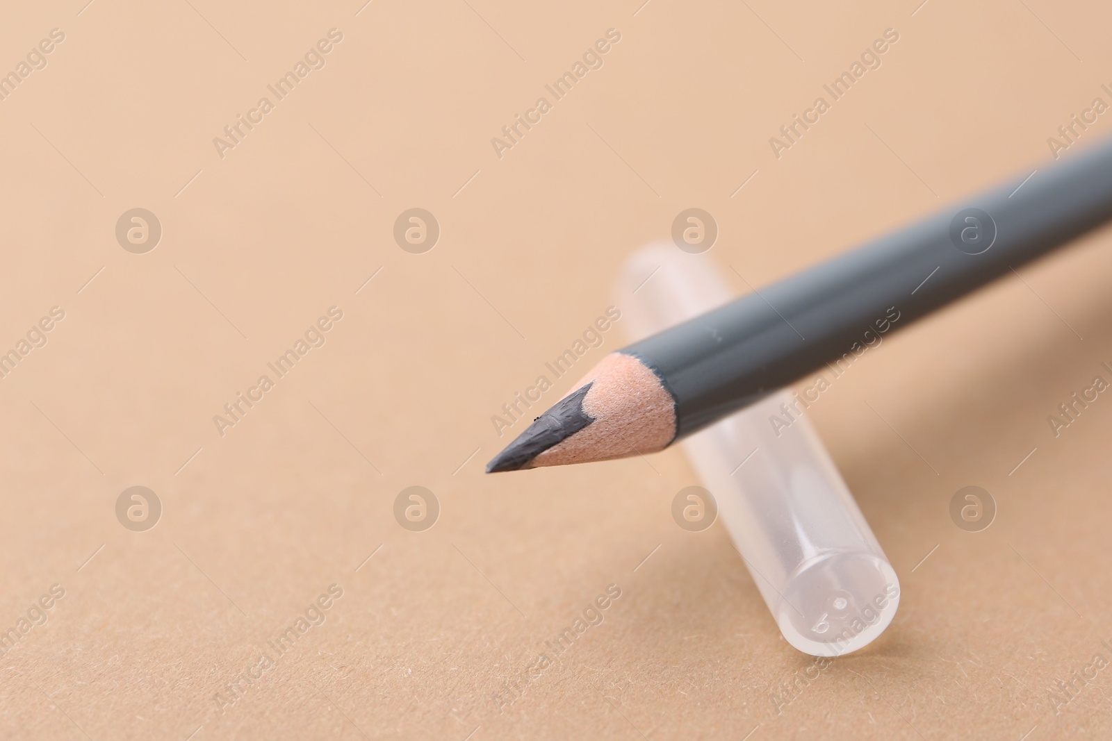 Grey eyebrow pencil on beige background, closeup. Space for text Photo of Grey eyebrow pencil on beige background, closeup. Space for text