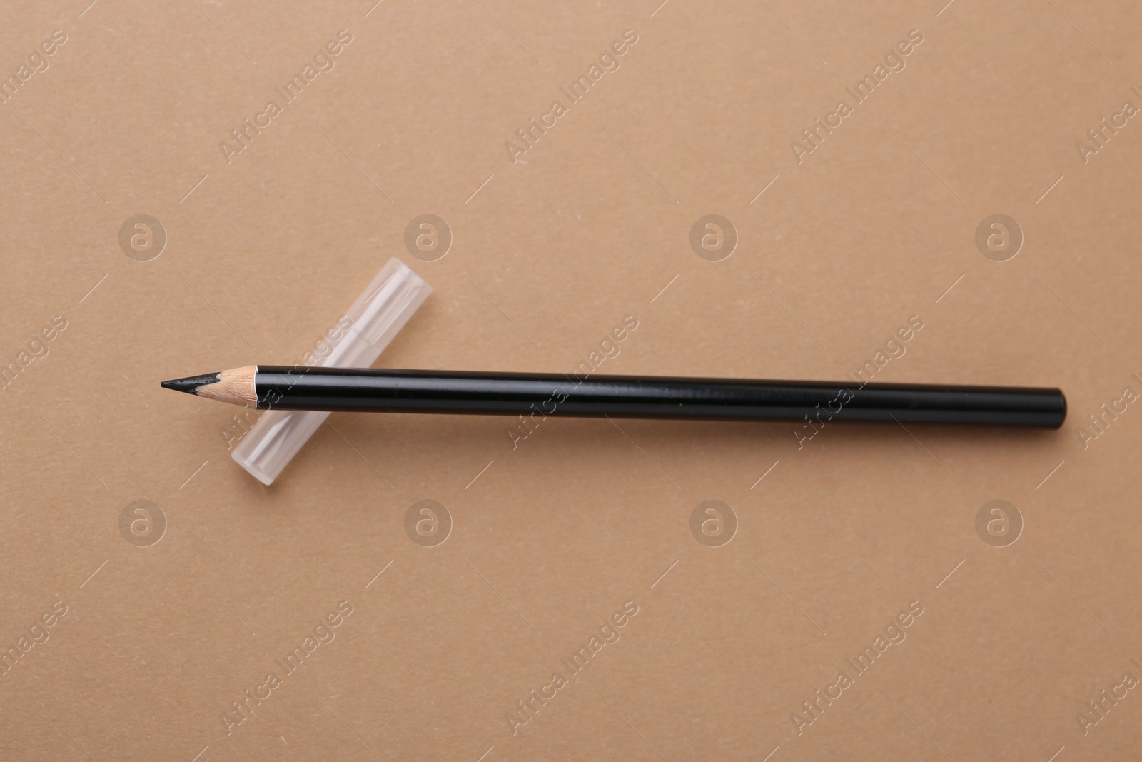 Black eyebrow pencil on beige background, top view Photo of Black eyebrow pencil on beige background, top view