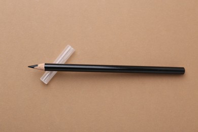 Photo of Black eyebrow pencil on beige background, top view