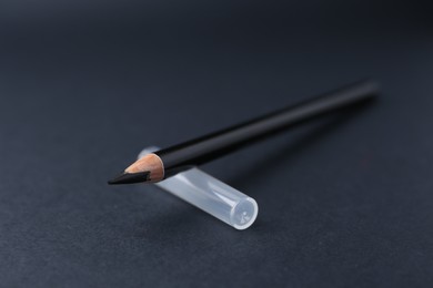 Photo of Black eyebrow pencil on dark background, closeup