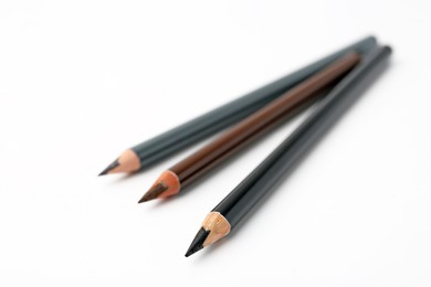 Photo of Three different eyebrow pencils on white background, closeup