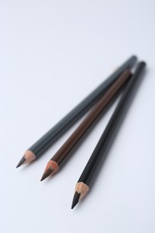 Photo of Three different eyebrow pencils on white background, closeup