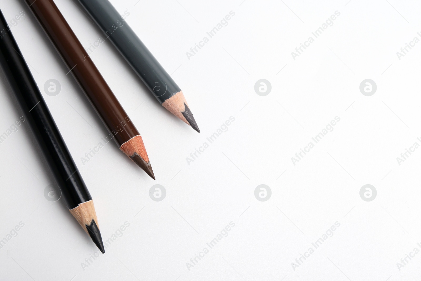Three different eyebrow pencils on white background, top view. Space for text Photo of Three different eyebrow pencils on white background, top view. Space for text