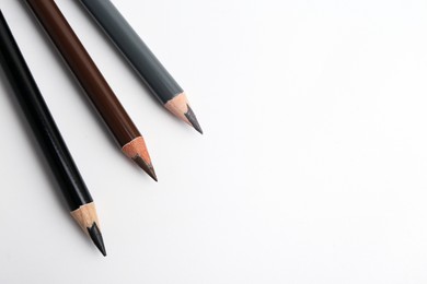 Photo of Three different eyebrow pencils on white background, top view. Space for text