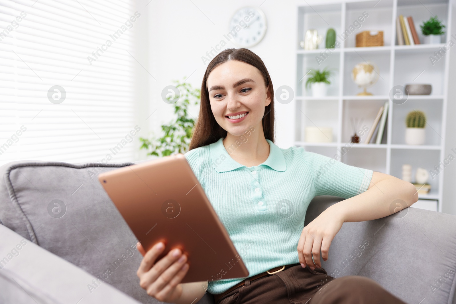 Young woman using modern tablet in armchair at home Photo of Young woman using modern tablet in armchair at home