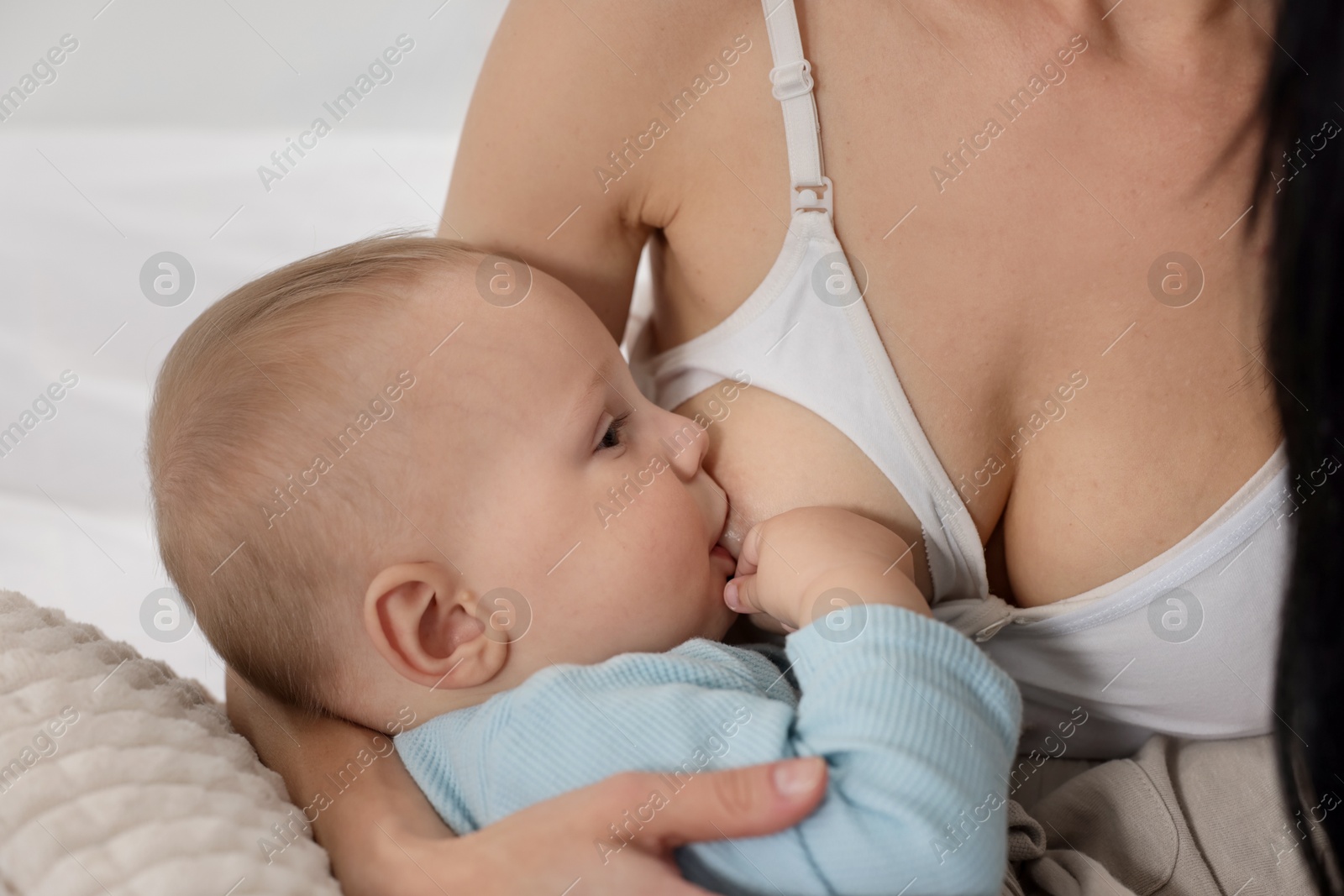 Photo of Mother breastfeeding her little baby indoors, closeup