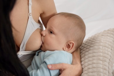 Photo of Mother breastfeeding her little baby indoors, closeup