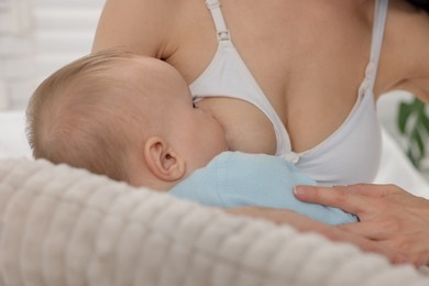 Photo of Mother breastfeeding her little baby indoors, closeup