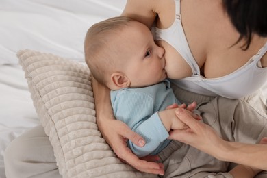 Photo of Mother breastfeeding her little baby indoors, closeup