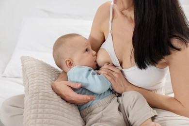 Photo of Mother breastfeeding her little baby on bed indoors, closeup