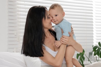 Photo of Smiling mother with her little baby on bed at home