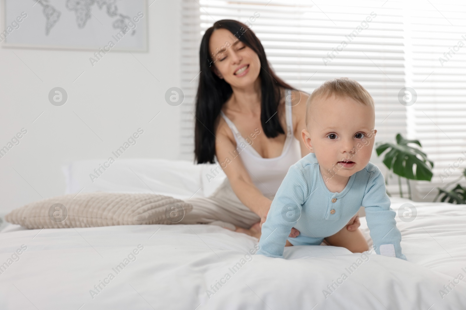 Smiling mother with her little baby on bed at home, selective focus Photo of Smiling mother with her little baby on bed at home, selective focus