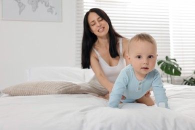 Photo of Smiling mother with her little baby on bed at home, selective focus