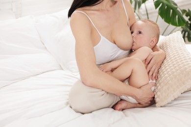 Photo of Mother breastfeeding her little baby on bed indoors, closeup