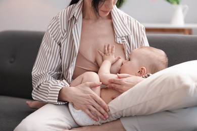 Photo of Mother breastfeeding her little baby on sofa indoors, closeup