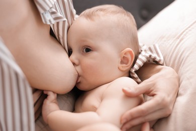 Photo of Mother breastfeeding her little baby indoors, closeup