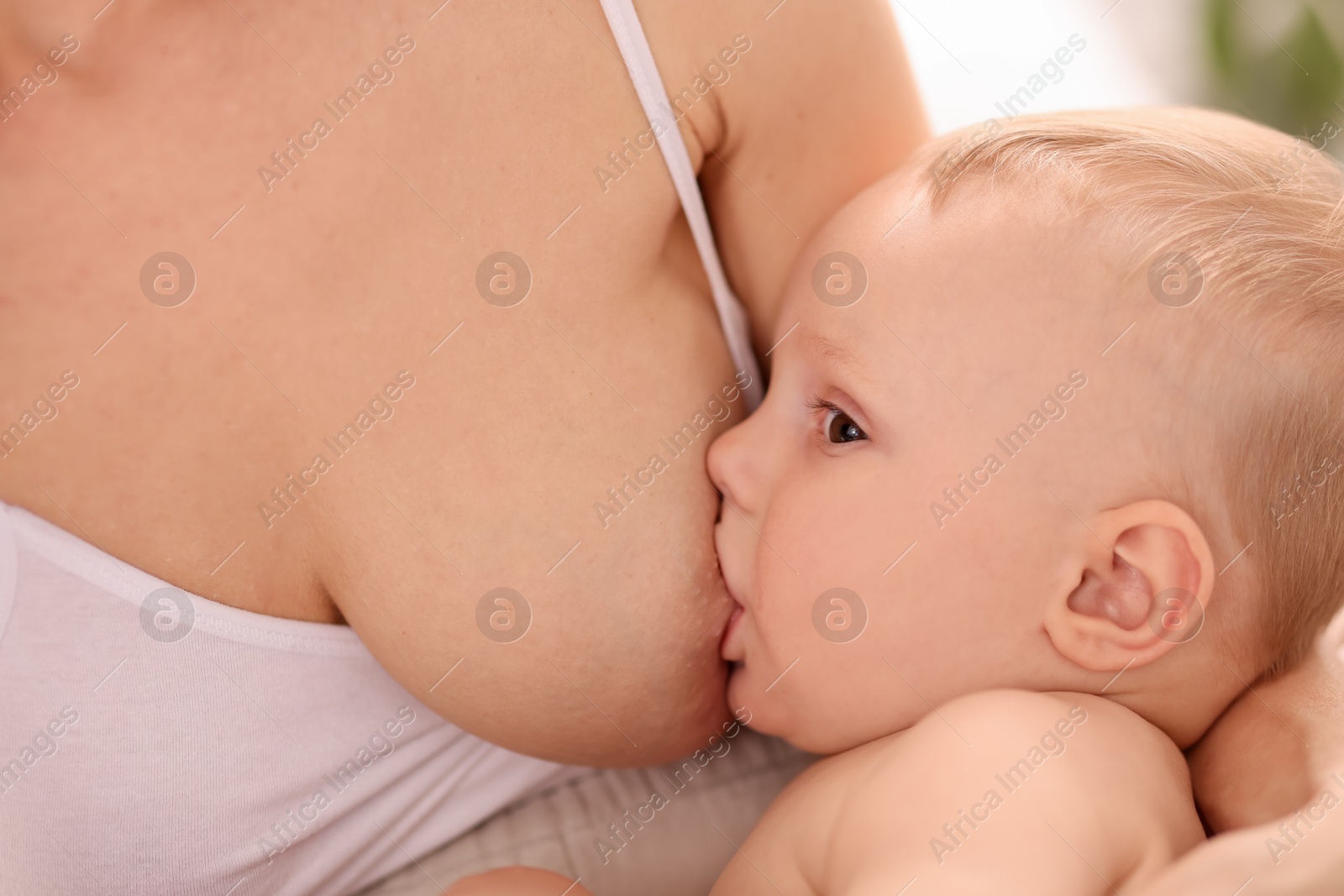 Photo of Mother breastfeeding her little baby indoors, closeup