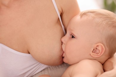 Photo of Mother breastfeeding her little baby indoors, closeup