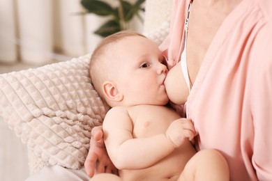 Photo of Mother breastfeeding her little baby indoors, closeup