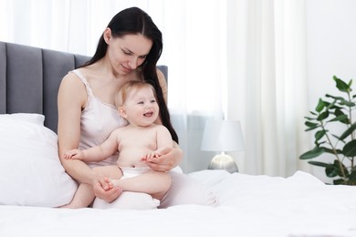 Photo of Mother with her happy little baby on bed at home. Space for text