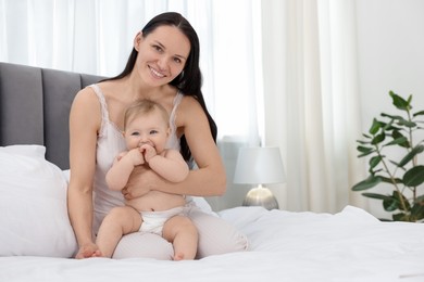 Photo of Smiling mother with her little baby on bed at home. Space for text