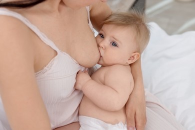 Photo of Mother breastfeeding her cute little baby indoors, closeup