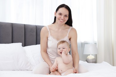 Photo of Smiling mother with her little baby on bed at home