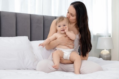 Photo of Mother kissing her little baby on bed at home