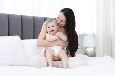 Photo of Smiling mother with her little baby on bed at home