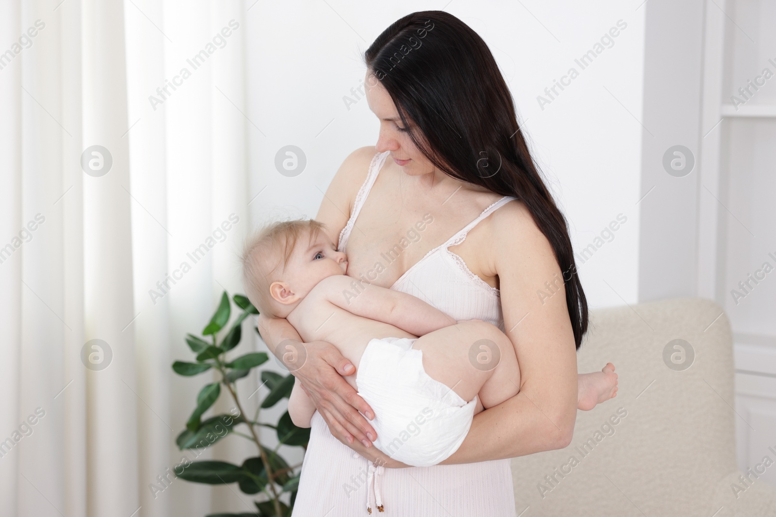 Mother breastfeeding her cute little baby indoors Photo of Mother breastfeeding her cute little baby indoors