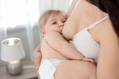 Photo of Mother breastfeeding her cute little baby indoors, closeup