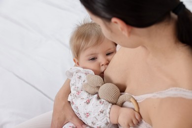 Photo of Mother breastfeeding her cute little baby on bed, closeup