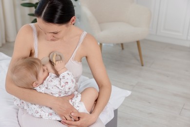 Photo of Mother breastfeeding her cute little baby indoors. Space for text