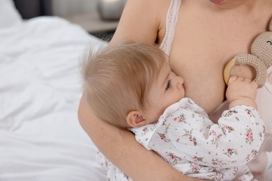 Photo of Mother breastfeeding her cute little baby on bed, closeup. Space for text