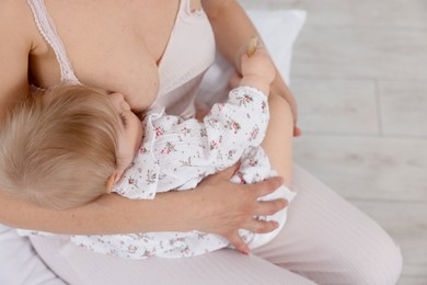 Photo of Mother breastfeeding her little baby indoors, closeup