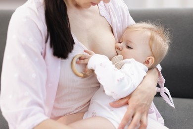 Photo of Mother breastfeeding her little baby on sofa indoors, closeup